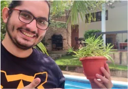 A man holding a potted plant next to a swimming pool