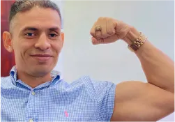 A man flexing his muscles in a blue shirt
