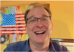 A man with glasses is smiling for the camera
