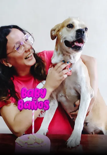 A woman holding a dog in front of a cake